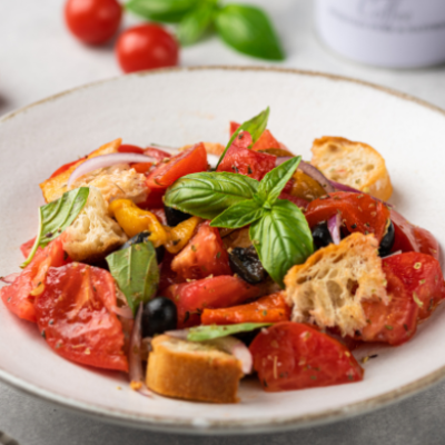 Ensalada panzanella italiana con tomate, pan tostado, cebolla morada, aceitunas y albahaca fresca