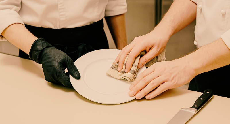 Dos manos colaborando en una cocina profesional, símbolo del trabajo en equipo y del valor del oficio gastronómico